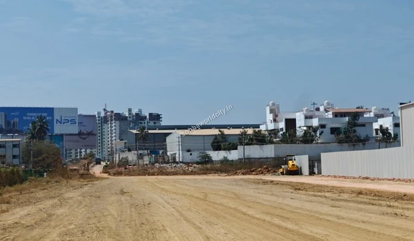 Dirt access road leading towards the main construction zone and distant city buildings at Sobha World City