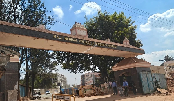 Wide shot of the MVJ Medical College entrance showing visitors and security staff active at the gate, situated near Sobha World City