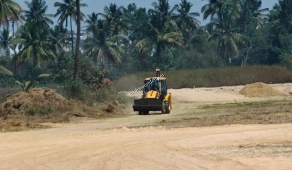 Construction vehicle operating on the dusty trail surrounded by palm trees at Sobha World City