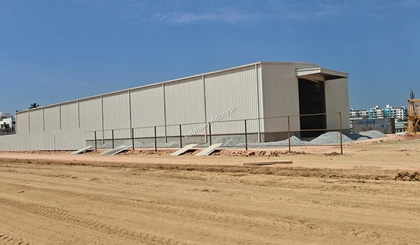 Yellow backhoe loader operating on the dirt pathway near the construction site of Sobha World City
