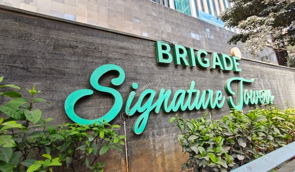 Lush greenery in front of the Brigade Signature Towers signage emphasizing the premium commercial workspaces near Sobha World City