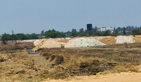 A deep excavated trench in the foreground with large piles of various colored construction soil in the background at Sobha World City