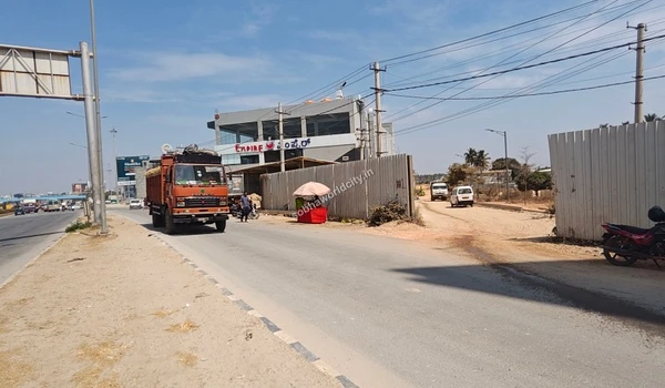 The immediate entrance to the Sobha World City site showing the boundary wall and the direct connection to the bustling Old Madras Road.