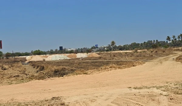 Intersection of dirt pathways with a distant billboard at Sobha World City