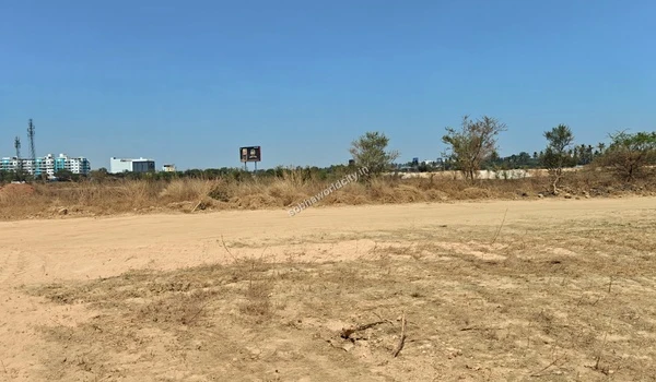 Flat dirt ground with dry grass and a distant billboard marking the boundary of the Sobha World City construction site