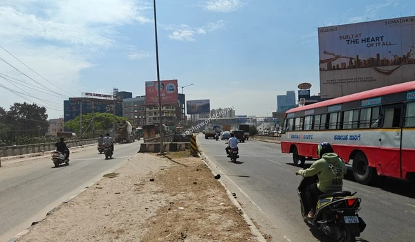 A vibrant view of the highway with a passing bus and two-wheelers, demonstrating the prime connectivity towards Hoskote right from Sobha World City.