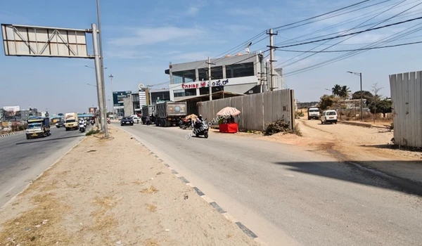 Wide angle perspective capturing the excellent road network, commercial signs, and infrastructure on KR Puram Hoskote Road at the Sobha World City turn-off.
