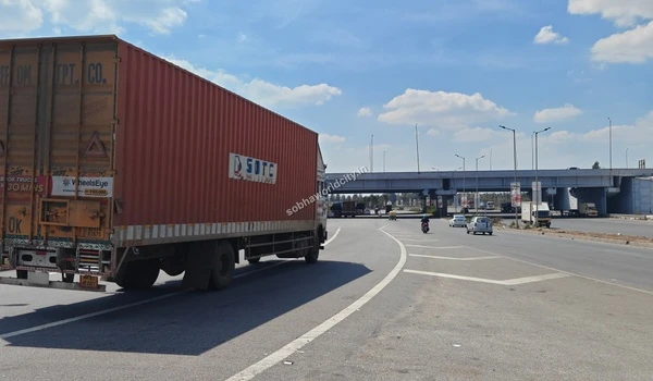 Heavy vehicles and freight transport smoothly navigating the robust underpass structure near the Sobha World City project.