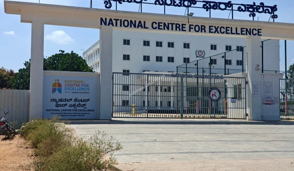 The clean white front structure of the Excellence Center visible from the main road near Sobha World City