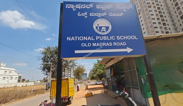National Public School directional board pointing right on Old Madras Road, guiding residents of Sobha World City seamlessly.