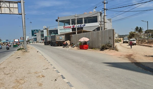 A clear daytime shot of the unpaved approach road leading into Sobha World City straight from the main commercial highway.