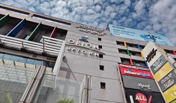 Striking exterior facade of Orion Uptown Mall showcasing major brands like Reliance Digital and Trends, located a short drive from Sobha World City