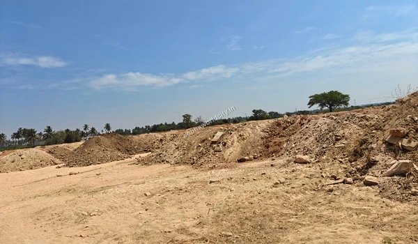 Large dirt mounds lining the edge of a sandy pathway at Sobha World City