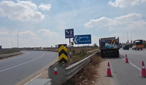 Large commercial container truck passing the Devanahalli turnoff, showcasing the robust, wide road network that services the Sobha World City area.