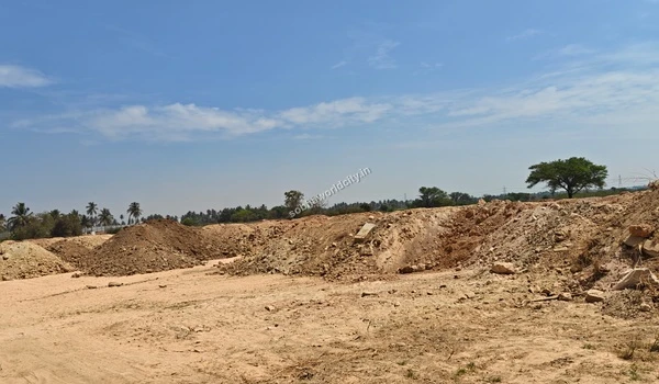 Wide sandy access road marked with vehicle tire tracks leading through the Sobha World City construction site