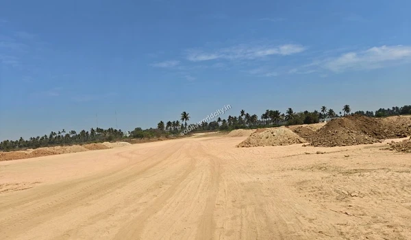 Extensive sandy terrain showing clear vehicle tracks and distant boundary trees at Sobha World City