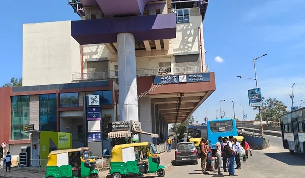 Passengers boarding buses under the modern Namma Metro track demonstrating seamless multimodal travel links for Sobha World City
