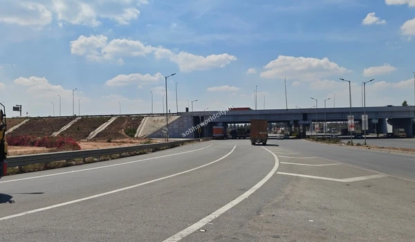 A commercial truck passing under the bridge, highlighting the congestion-free connectivity and wide lanes near Sobha World City.