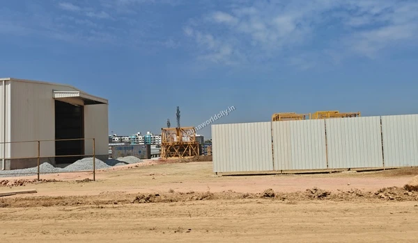 View of the white metal warehouse standing alongside yellow construction trusses at the Sobha World City project